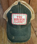 Distressed green trucker hat with tan mesh back and a rectangular patch reading You Serious Clark?
