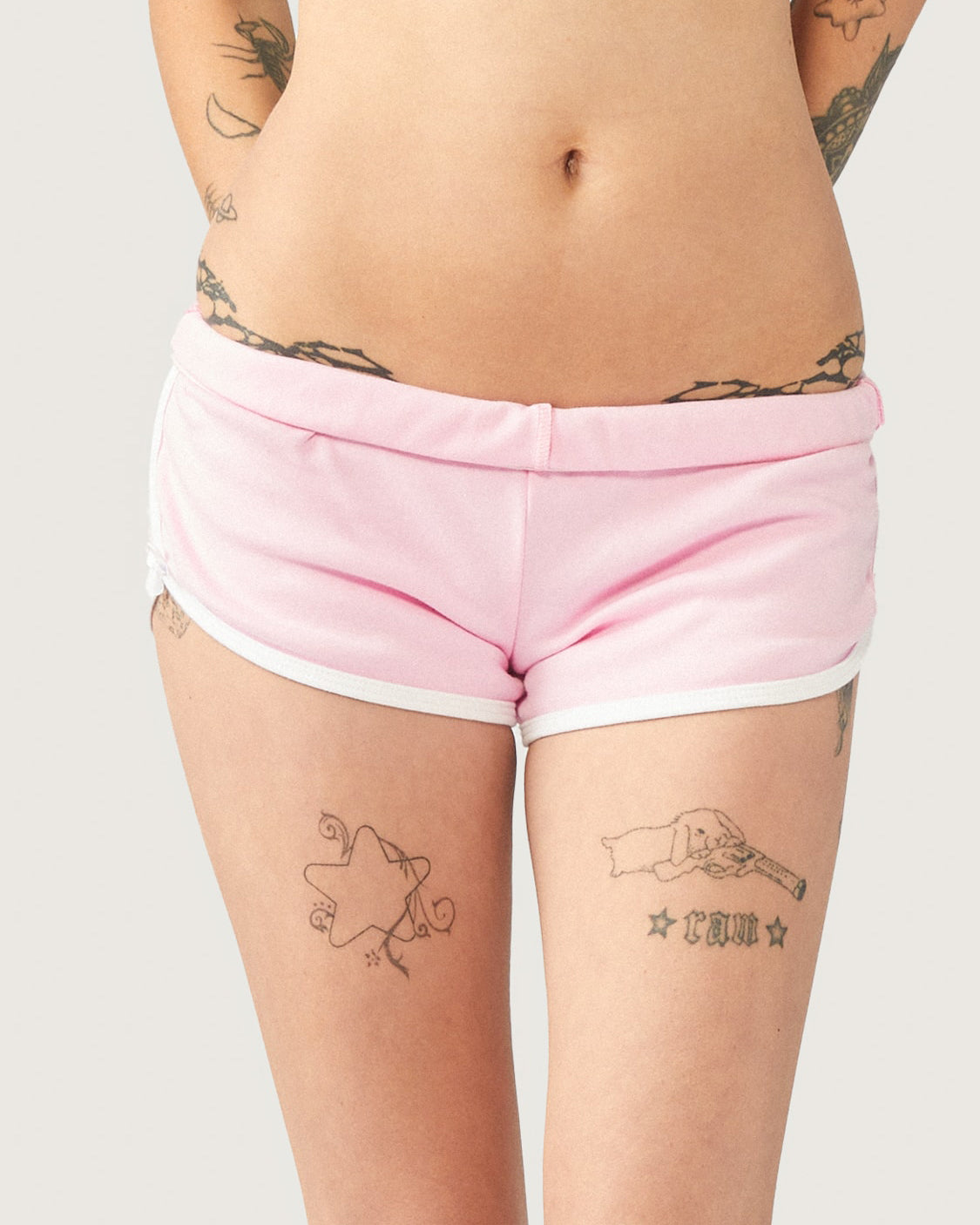 Pastel pink Kitty Girl booty shorts with white trim, signature bows, and rhinestone detail on the back.