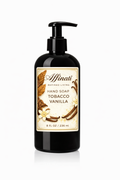 A black bottle of Tobacco Vanilla hand soap with a pump dispenser, featuring a label with tobacco leaf and vanilla flower illustrations.