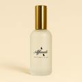 A 4 oz bottle of white tea room and linen spray with a frosted glass body and gold cap.