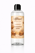 A clear plastic bottle of Cinnamon Swirl Shampoo with a black cap, featuring a label with cinnamon rolls and cinnamon sticks.