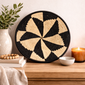 Handwoven monochrome pinwheel wicker basket featuring a black and natural geometric pattern on a neutral wall.