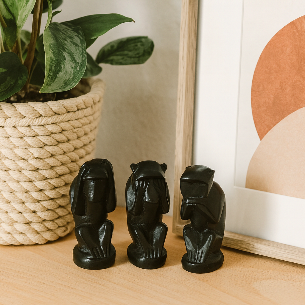 Three handcrafted matte black African blackwood chimpanzee figurines on a minimalist shelf