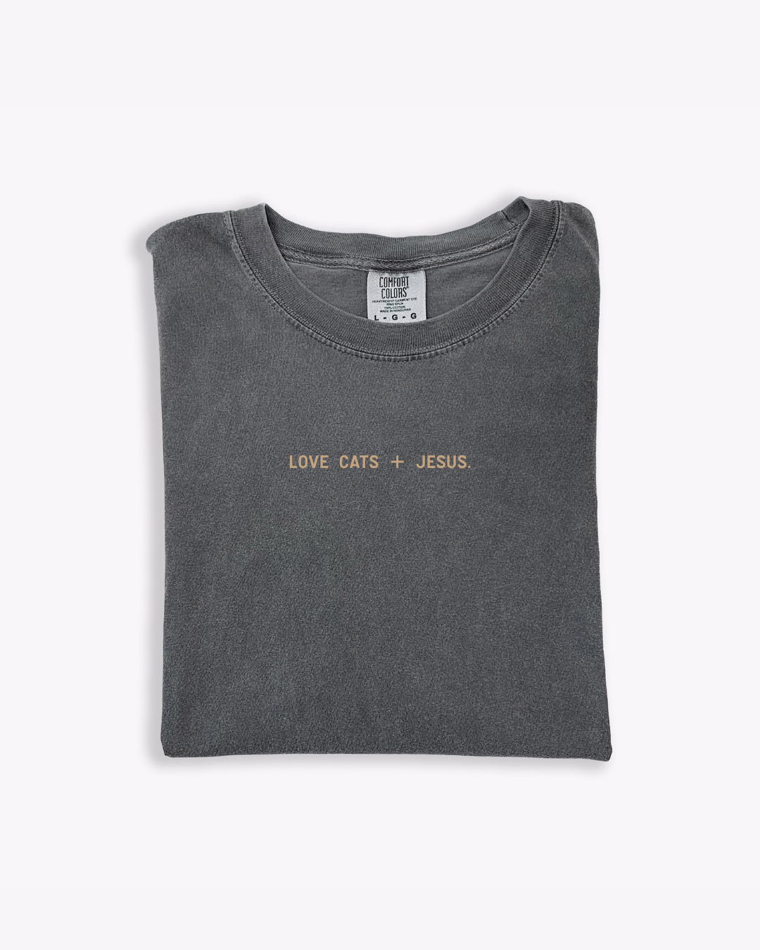 Minimalist graphic tee featuring Love Cats + Jesus text on a Comfort Colors garment-dyed cotton shirt.