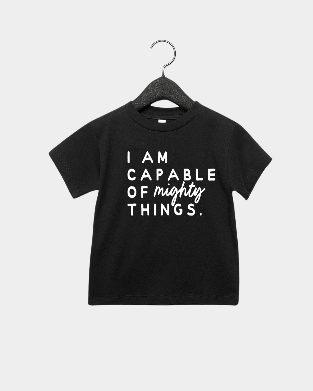 Child wearing an I am Capable of Mighty Things graphic tee in white