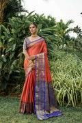 Vibrant orange Kanjivaram silk saree featuring zari weaving and a contrast blue blouse.