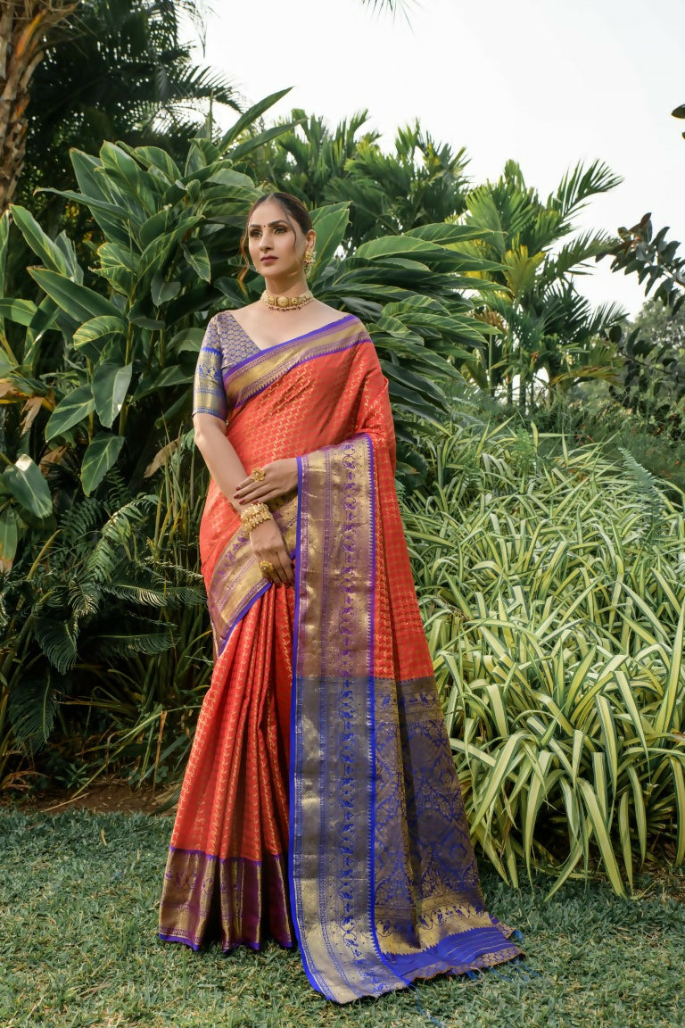 Vibrant orange Kanjivaram silk saree featuring zari weaving and a contrast blue blouse.