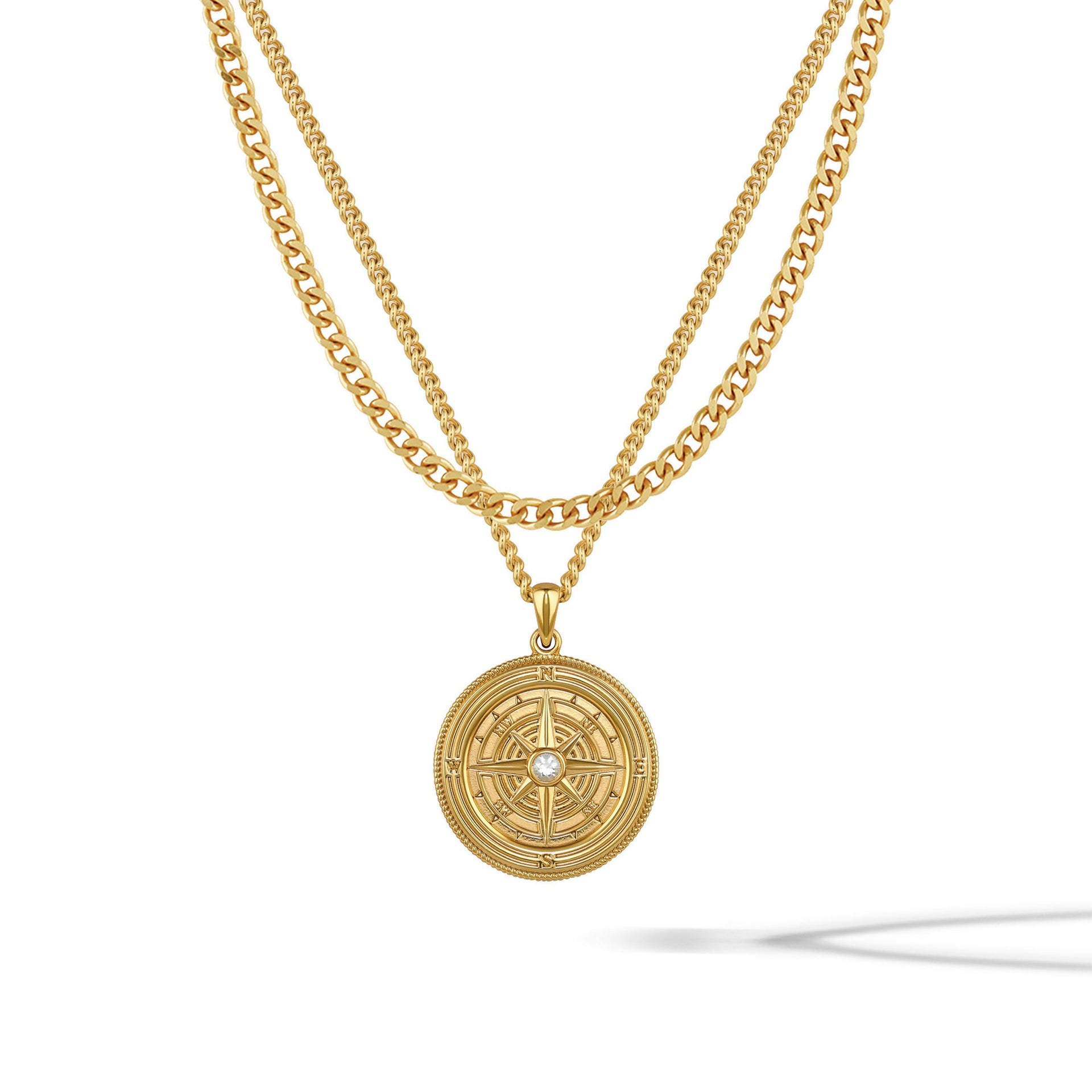 Gold-toned compass pendant featuring a central sapphire stone on a classic curb chain.