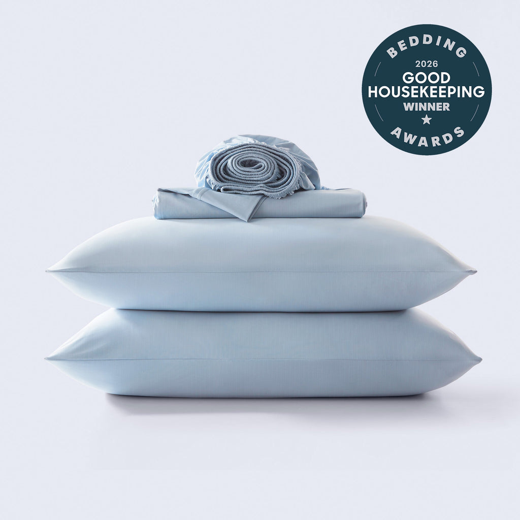 A stack of light blue cooling bed sheets and pillowcases on a white background, featuring a 2026 Good Housekeeping Bedding Award seal.