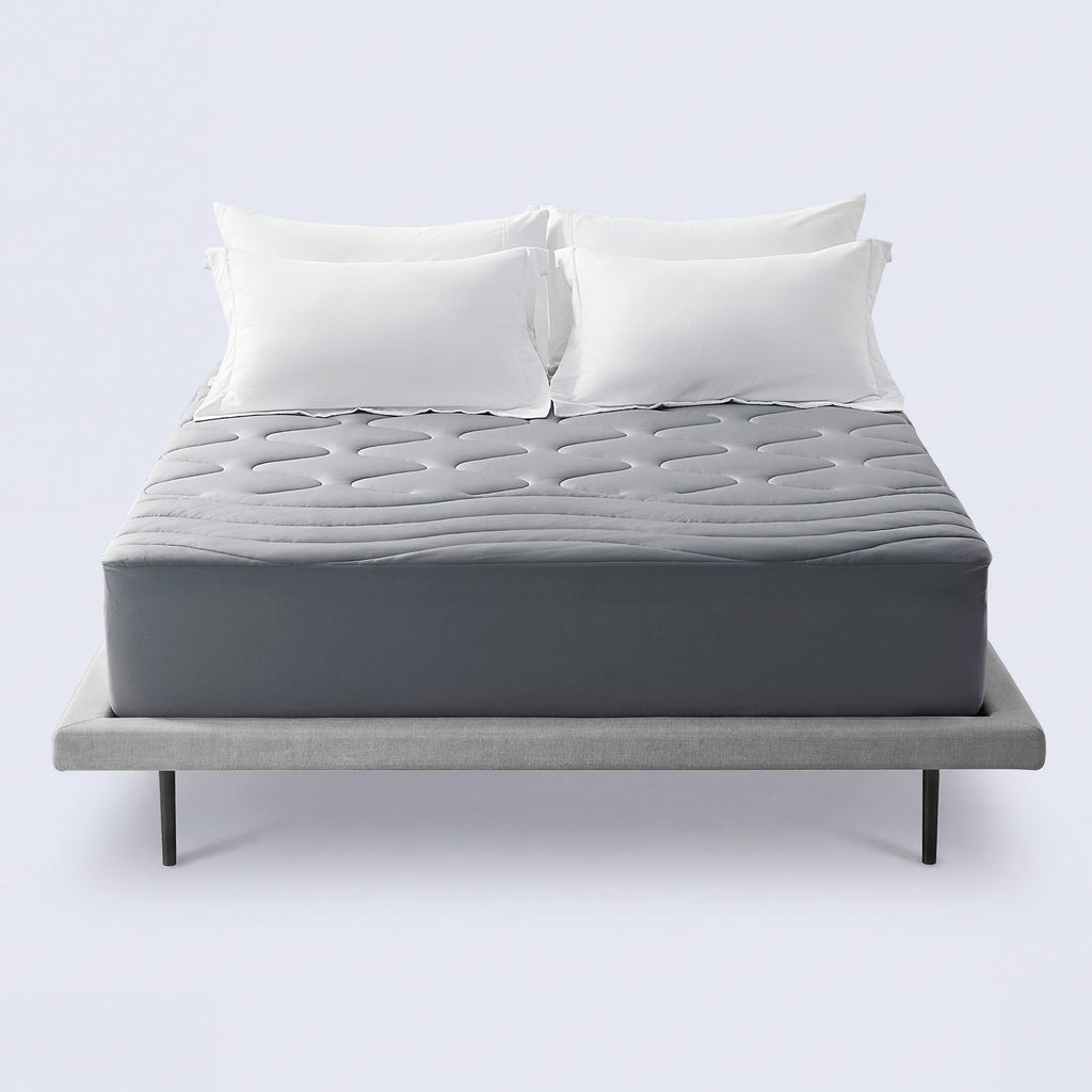 Grey cooling mattress topper on a bed with white pillows