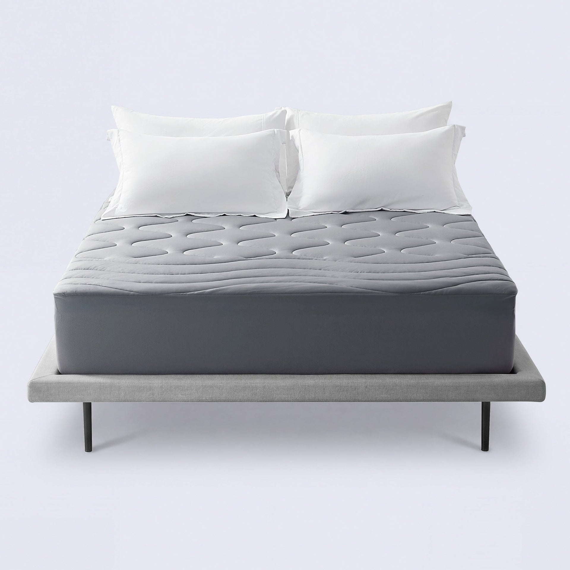 Grey cooling mattress topper on a bed with white pillows