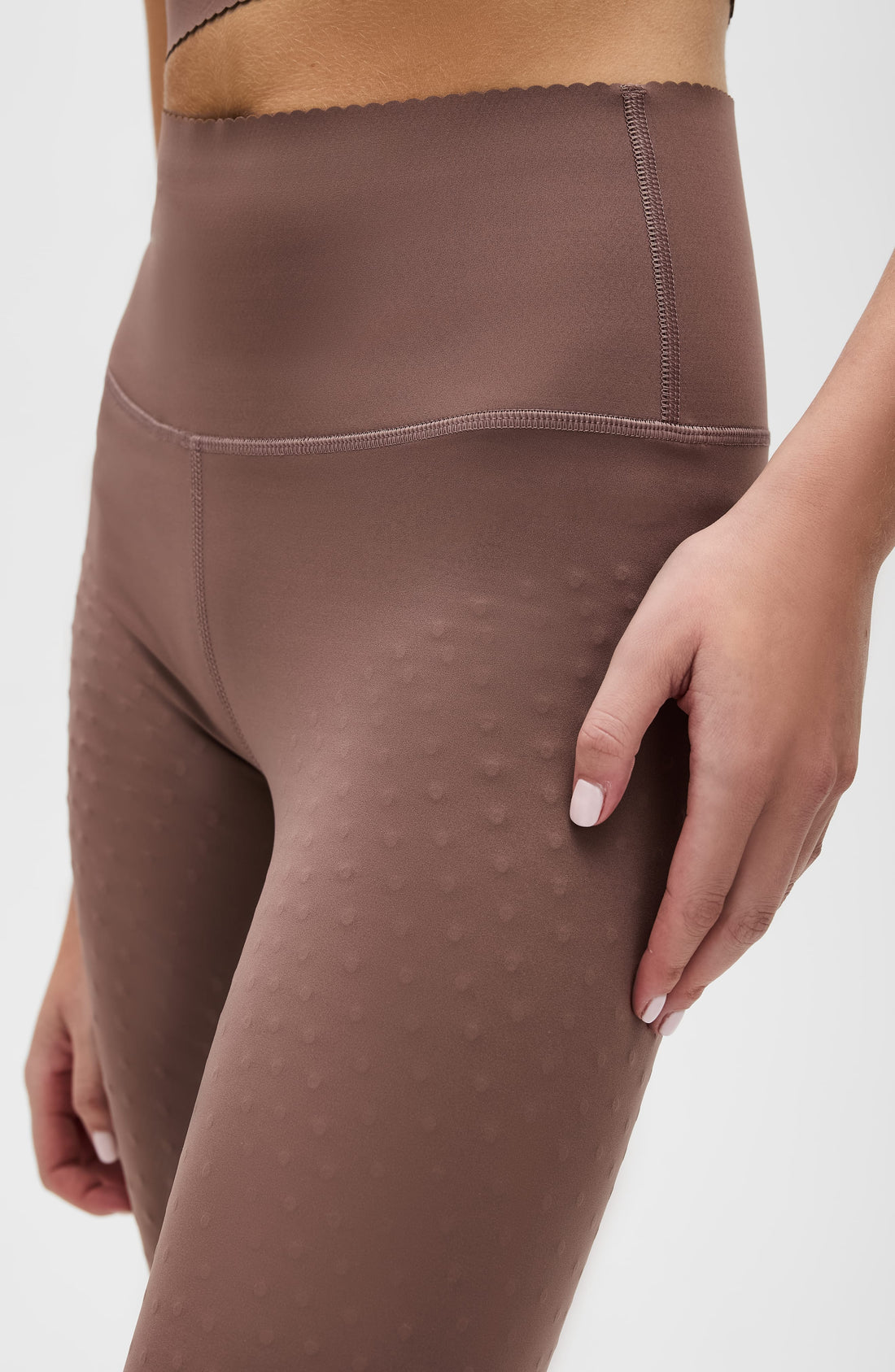 Woman wearing brown Adorn high-waisted sculpting leggings with scalloped hem detail