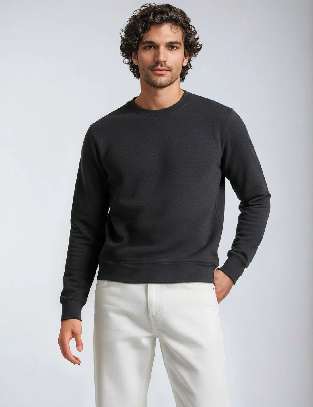 Model wearing a dark charcoal grey midweight crew neck fleece sweatshirt with ribbed cuffs and hem.