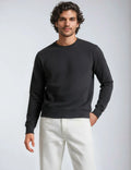 Model wearing a dark charcoal grey midweight crew neck fleece sweatshirt with ribbed cuffs and hem.