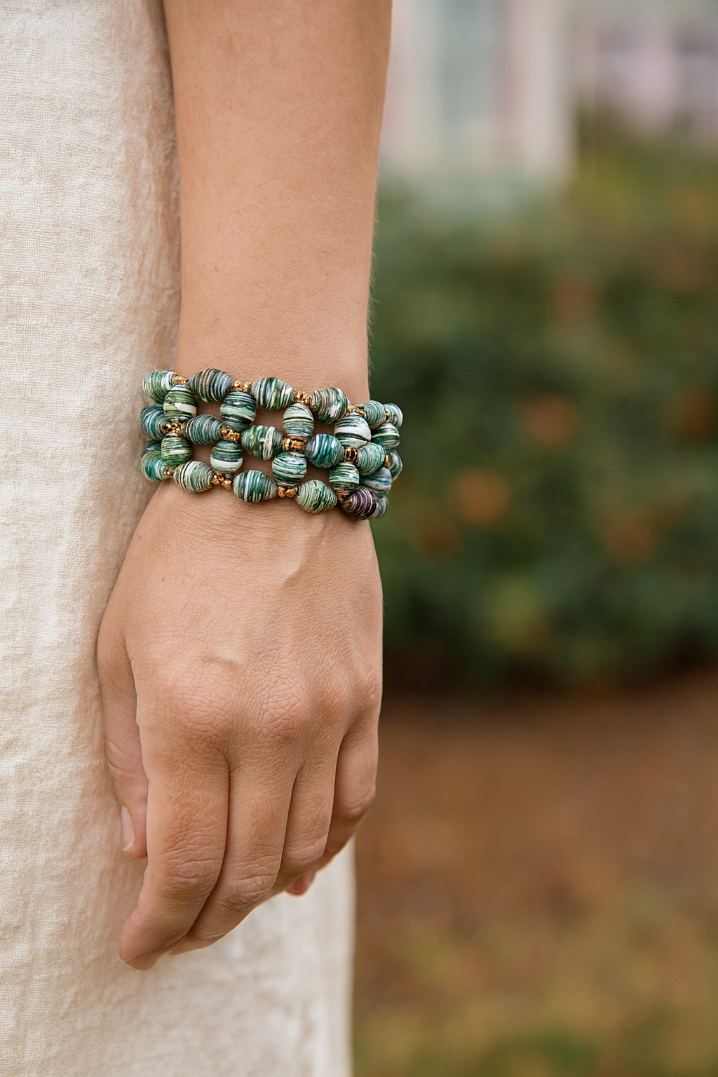Multicolor geometric Ugandan paper bead stretch cuff bracelet with gold spacer beads on a wrist