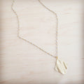 Gold-tone diamond-shaped wavy pendant necklace with a beaded chain on a light wooden background