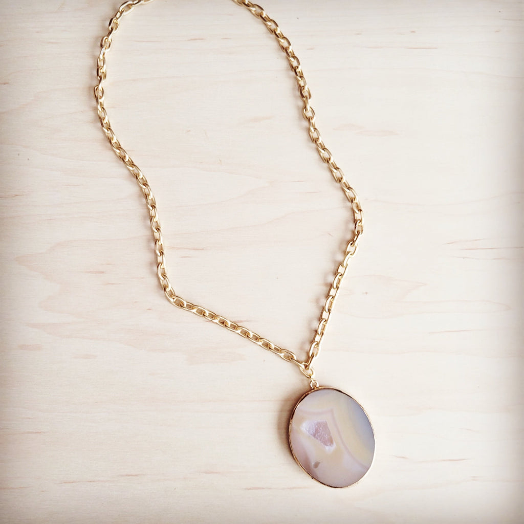 Matte gold gilded agate pendant on a gold-tone oval link chain, showcasing natural stone banding and a crystal center.