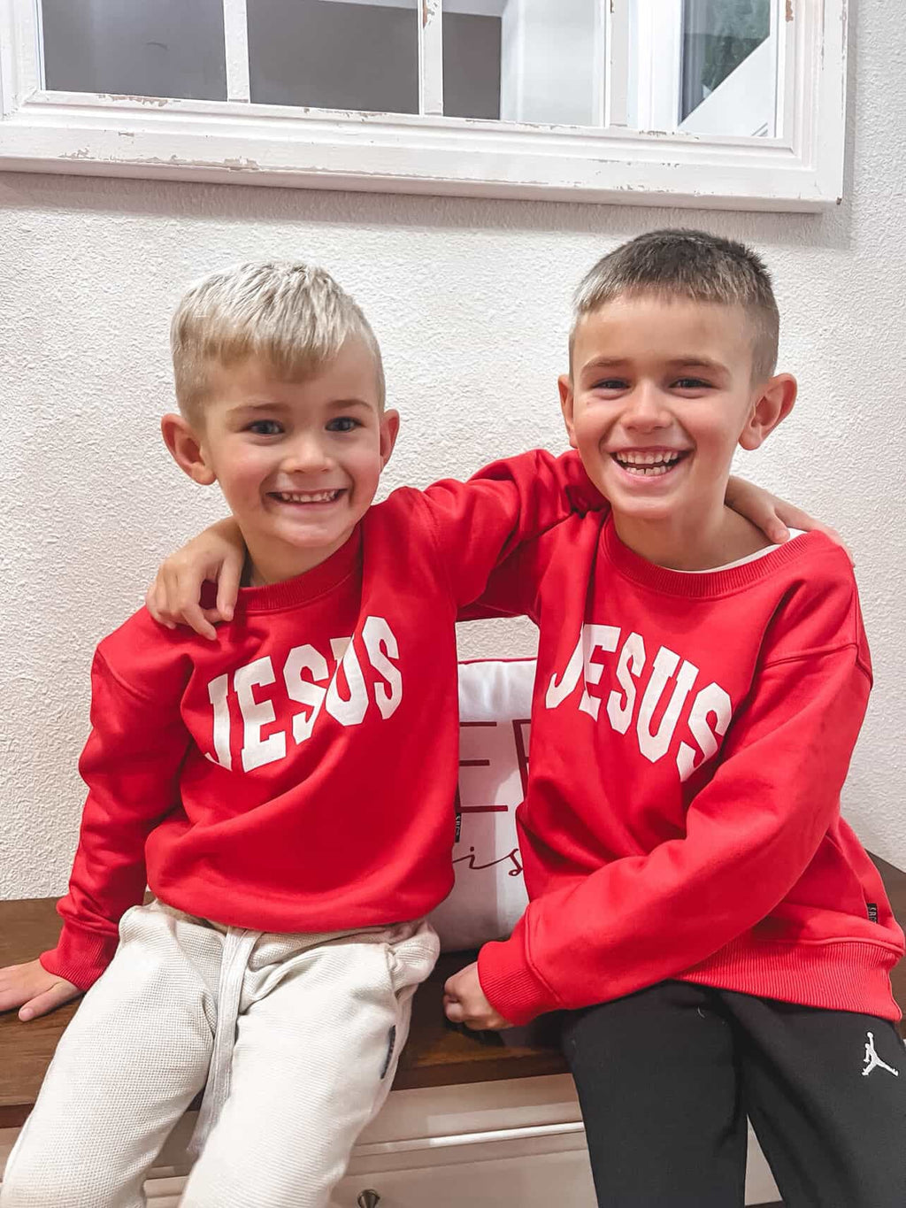 Child wearing a black Jesus Varsity Crew sweatshirt with clean white lettering.