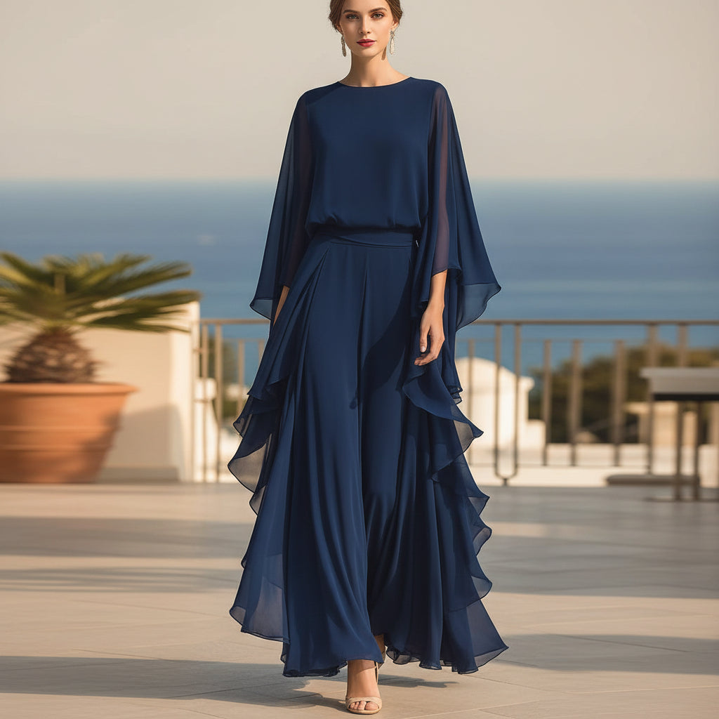 Woman wearing a deep blue two-piece set featuring a ruffled batwing sleeve top and matching wide-leg trousers.