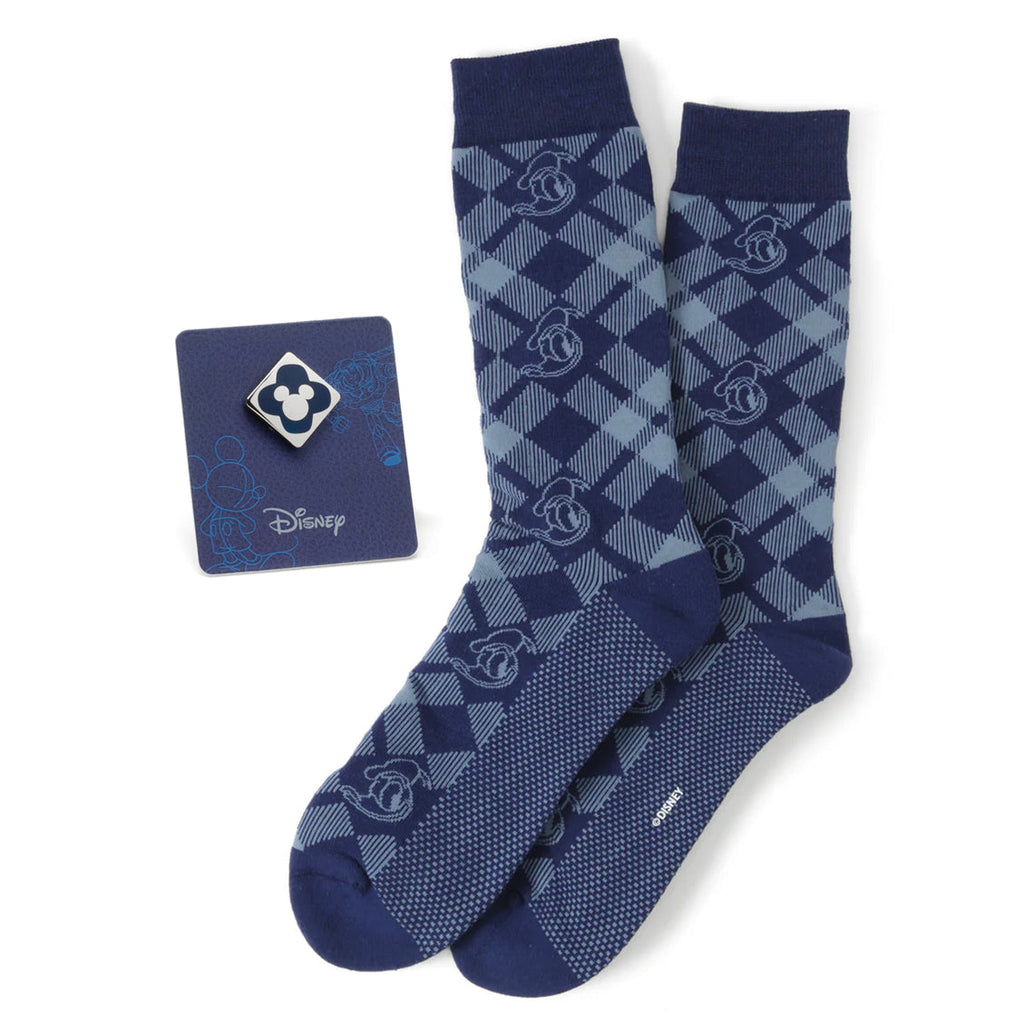A pair of blue plaid patterned crew socks featuring Donald Duck characters, paired with a blue Mickey Mouse enamel lapel pin on a display card.