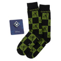 A pair of black and green checkered socks featuring Goofy next to a blue Mickey Mouse enamel lapel pin on a display card.