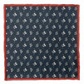 A navy silk pocket square with a white print of Mickey Mouse, Donald Duck, and Pluto with a burgundy border, displayed flat and inside a suit jacket pocket.