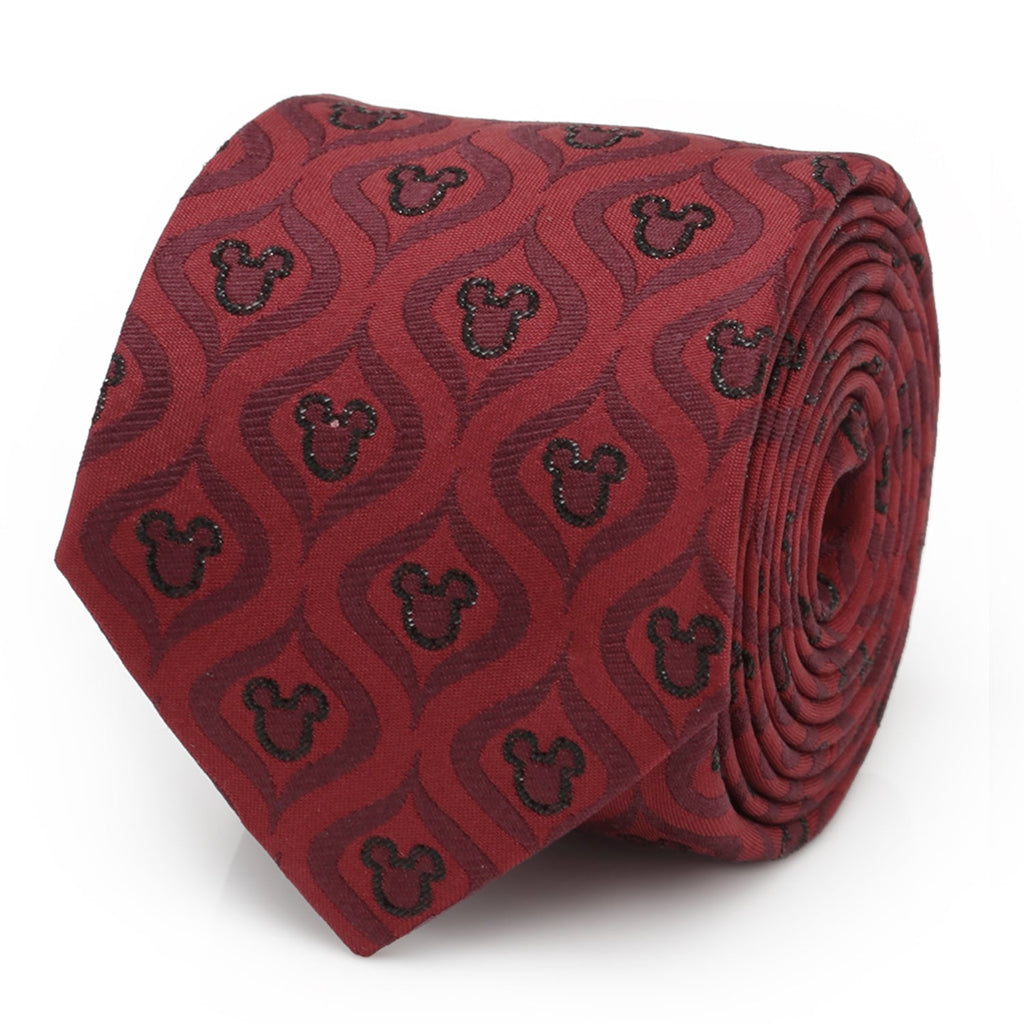 A festive red silk necktie with a black geometric pattern and Mickey Mouse icons, displayed on a suit and shirt.