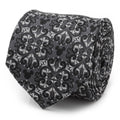 Close up of a gray and silver silk tie with a damask pattern and hidden Mickey Mouse motifs rolled on a white surface.