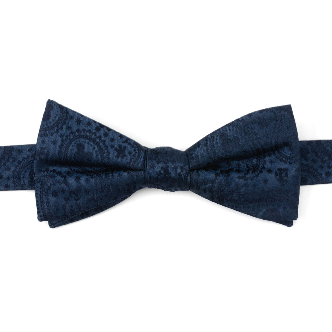 Close up of a navy blue silk bow tie featuring a subtle paisley print with Mickey Mouse head silhouettes.