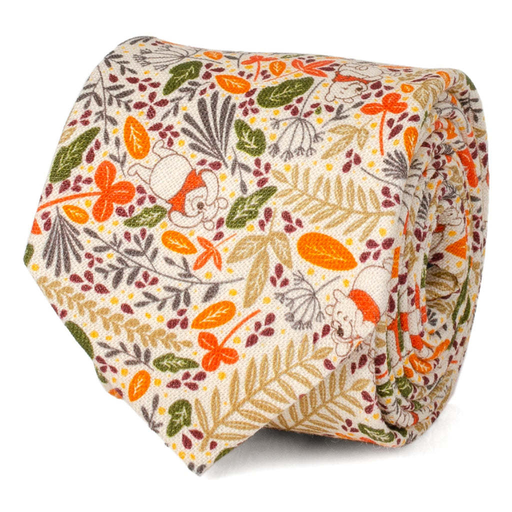 Close up of a tan linen necktie featuring a Winnie the Pooh and autumn leaf pattern, displayed on a suit jacket