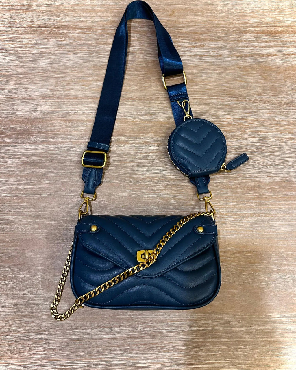 Blue handbag with gold chain and strap on a wooden surface