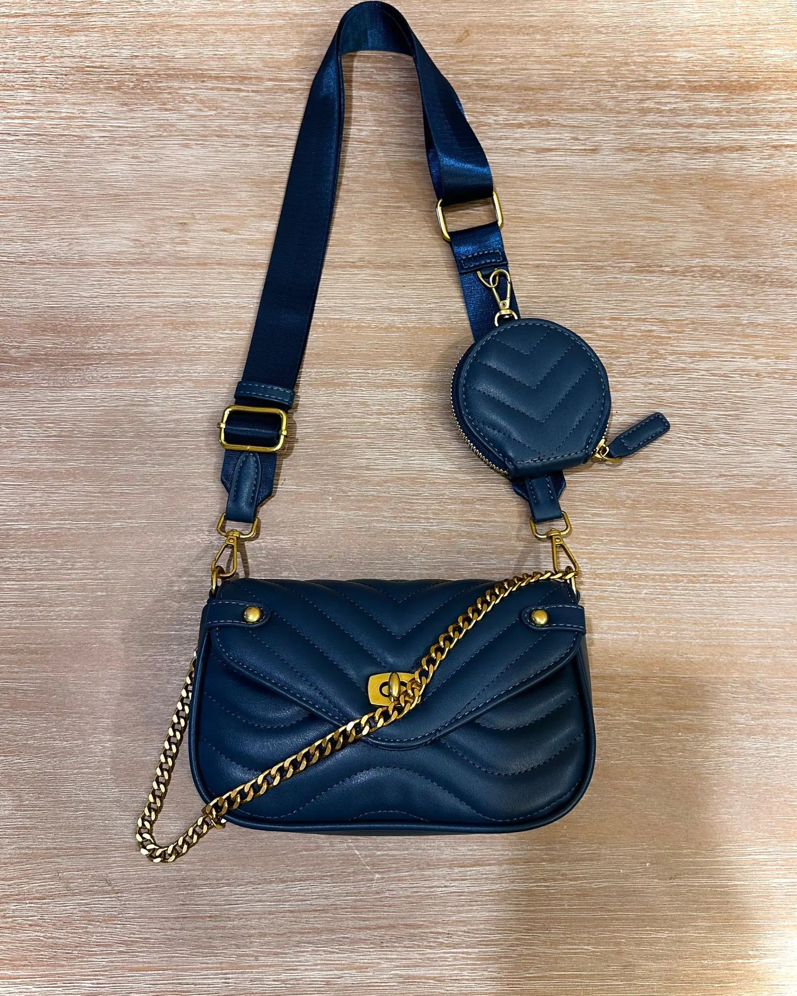 Blue handbag with gold chain and strap on a wooden surface