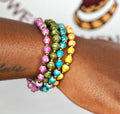 Set of 4 bohemian paper bead bracelets featuring purple, olive-green, turquoise, orange, and gold accents.