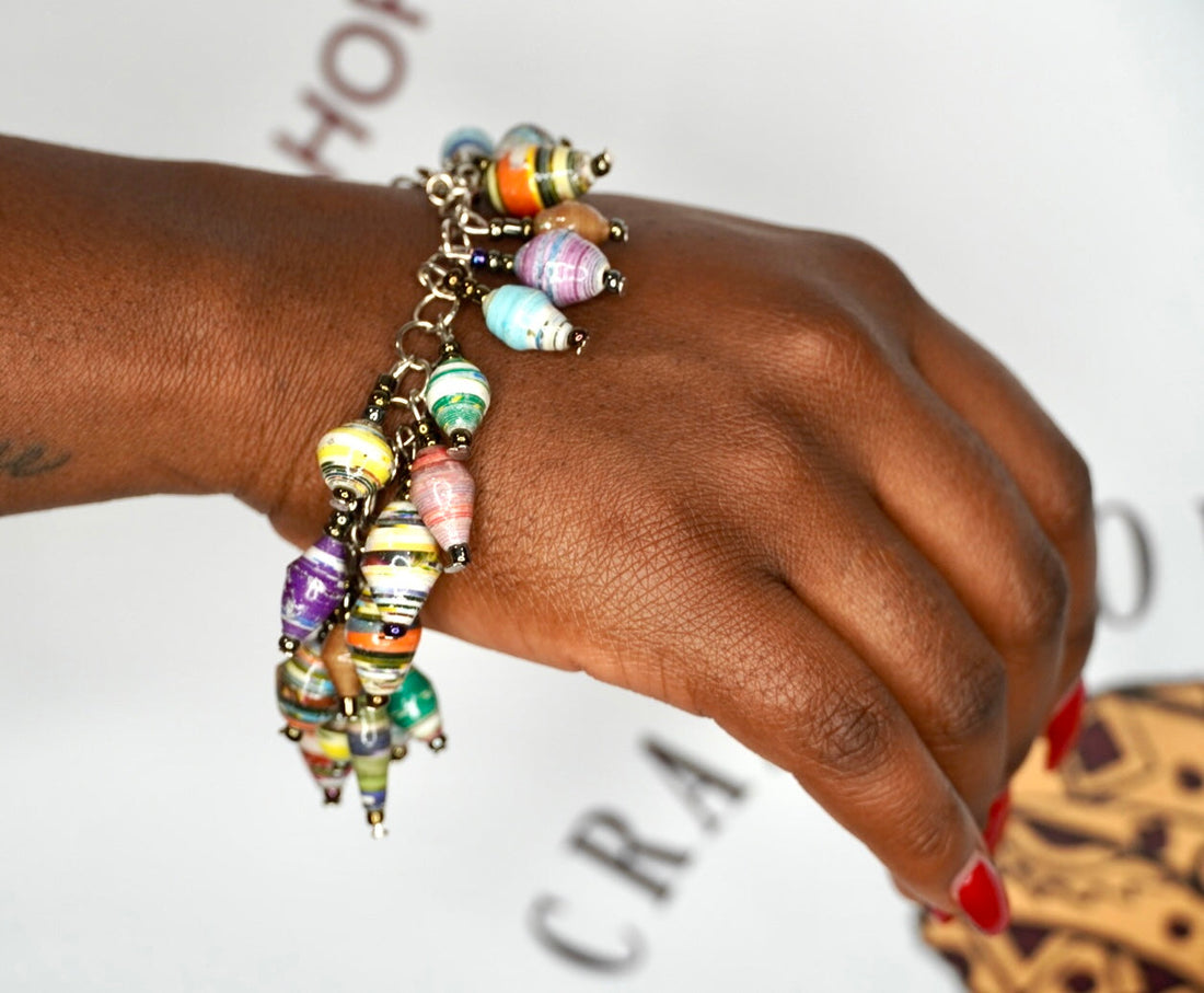 Close up of a vibrant bohemian charm bracelet made of multicolored Ugandan paper beads and silver accents.