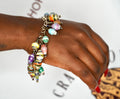 Close up of a vibrant bohemian charm bracelet made of multicolored Ugandan paper beads and silver accents.