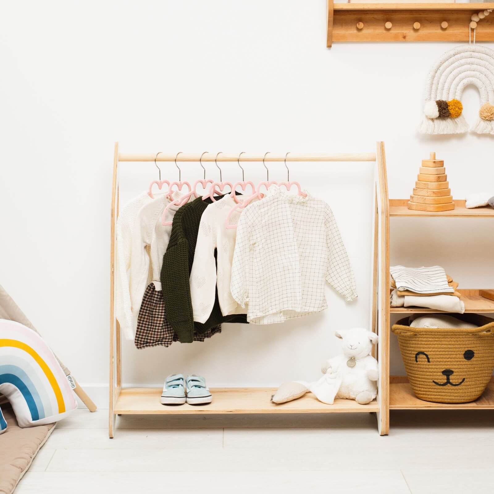 Minimalist wooden clothing rack for kids standing in a nursery for Montessori style organization