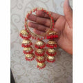 Gold-toned bangles featuring red pearls and hanging jhumka latkans