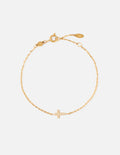 Dainty gold-tone link bracelet featuring a small cross charm with a gemstone detail