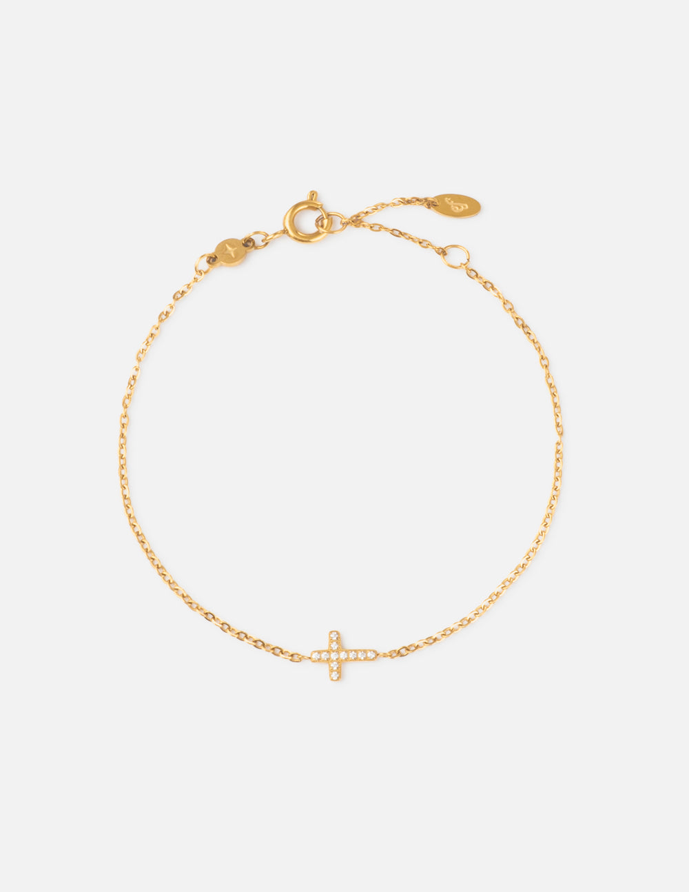 Dainty gold-tone link bracelet featuring a small cross charm with a gemstone detail