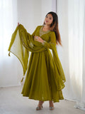 Woman wearing a monochromatic olive green midi kurta set with sequence embroidery and long sleeves.