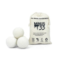 Set of 6 white wool dryer balls in a canvas bag on a laundry room surface