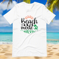 White graphic t-shirt with Beach Mode text and palm tree design on a beach background.