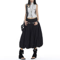 Model wearing a black elastic high waist pleated bubble A-line midi skirt, paired with a white sleeveless top and black sandals, showcasing the skirt's voluminous silhouette.