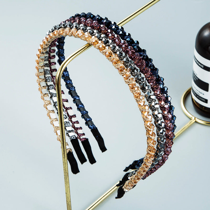 A collection of Winding String Crystal Headbands in various colors including blue, gold, silver, and purple, displayed on a gold stand, highlighting their sparkling crystals.