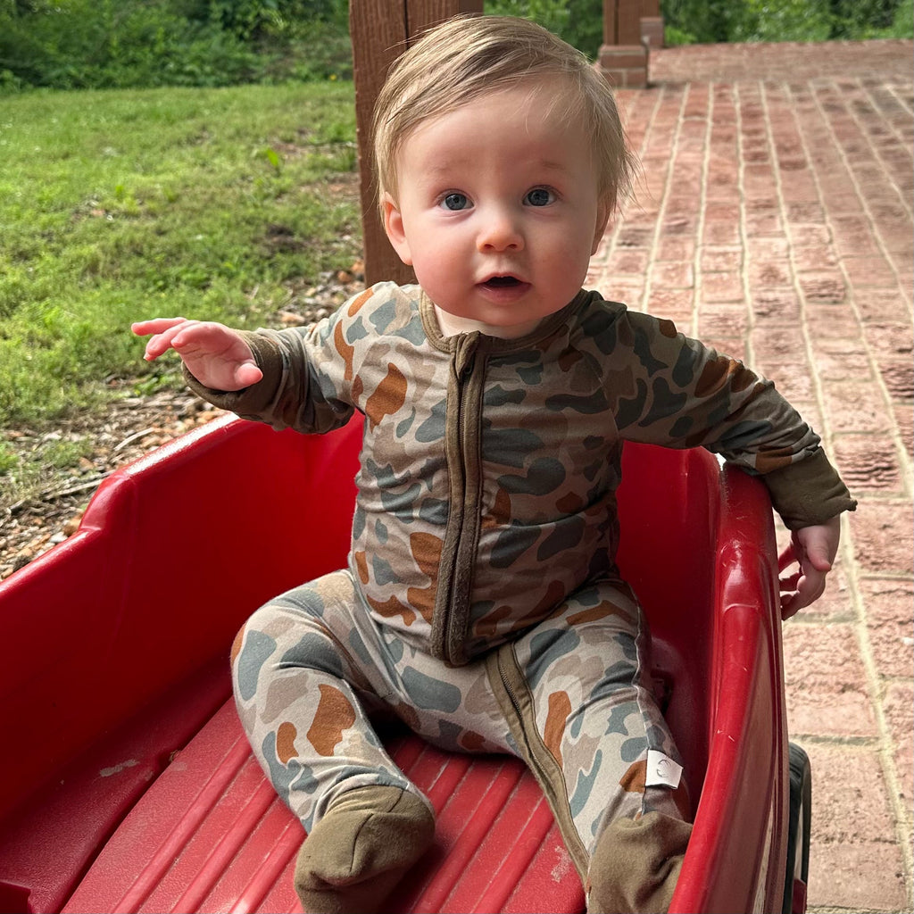 Camo print baby zippy in olive green, tan, and rust brown with fold-over cuffs.