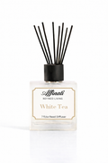 A square glass bottle of Affinati White Tea Reed Diffuser with black reeds on a marble surface.