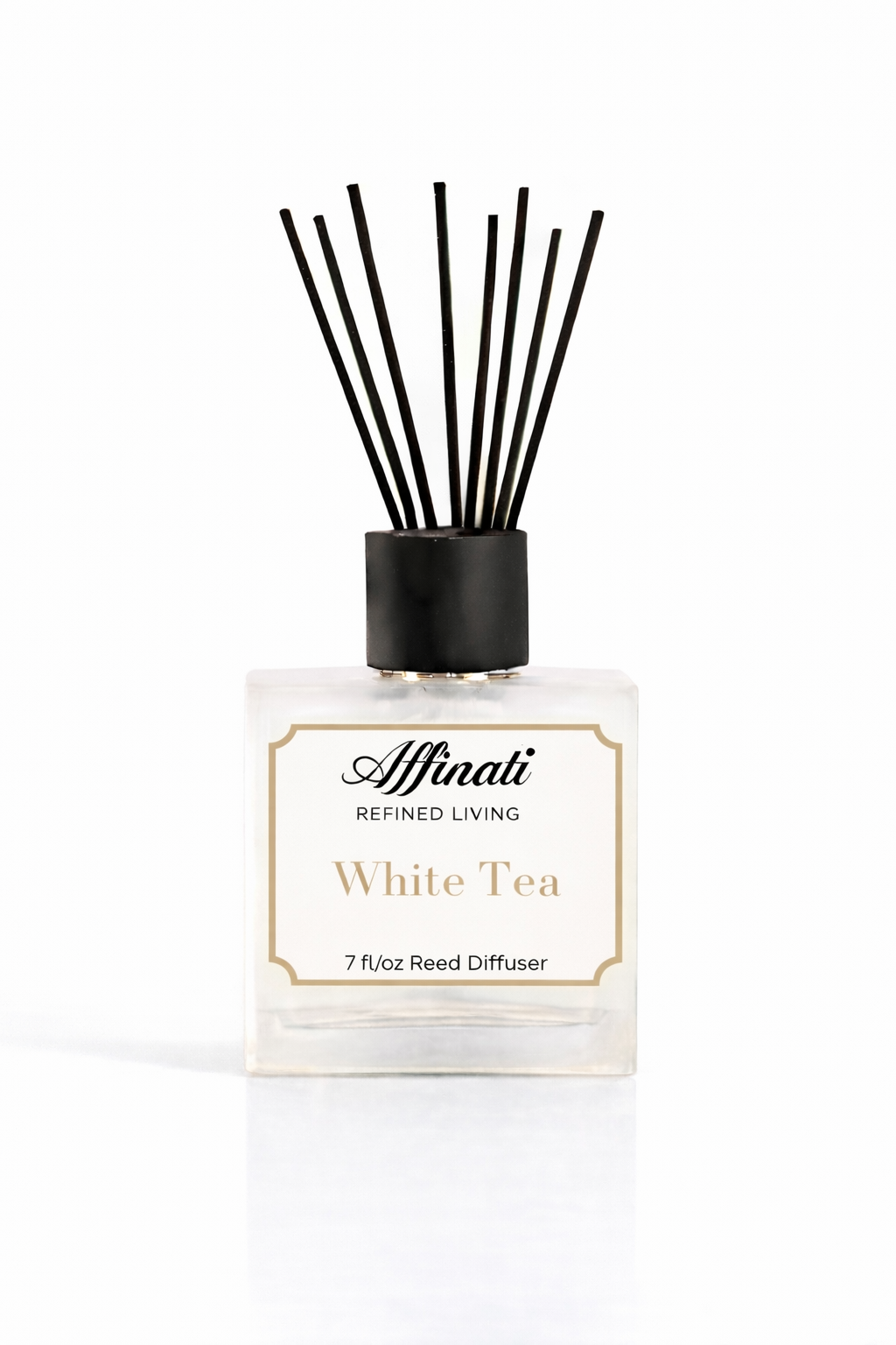A square glass bottle of Affinati White Tea Reed Diffuser with black reeds on a marble surface.