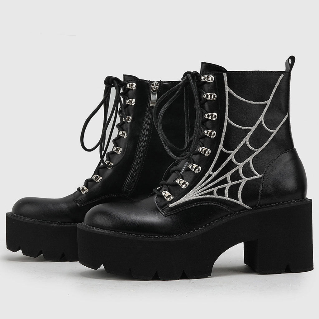 A pair of black women's platform combat boots with silver spiderweb embroidery, lace-up front, and side zipper, displayed on a white background.