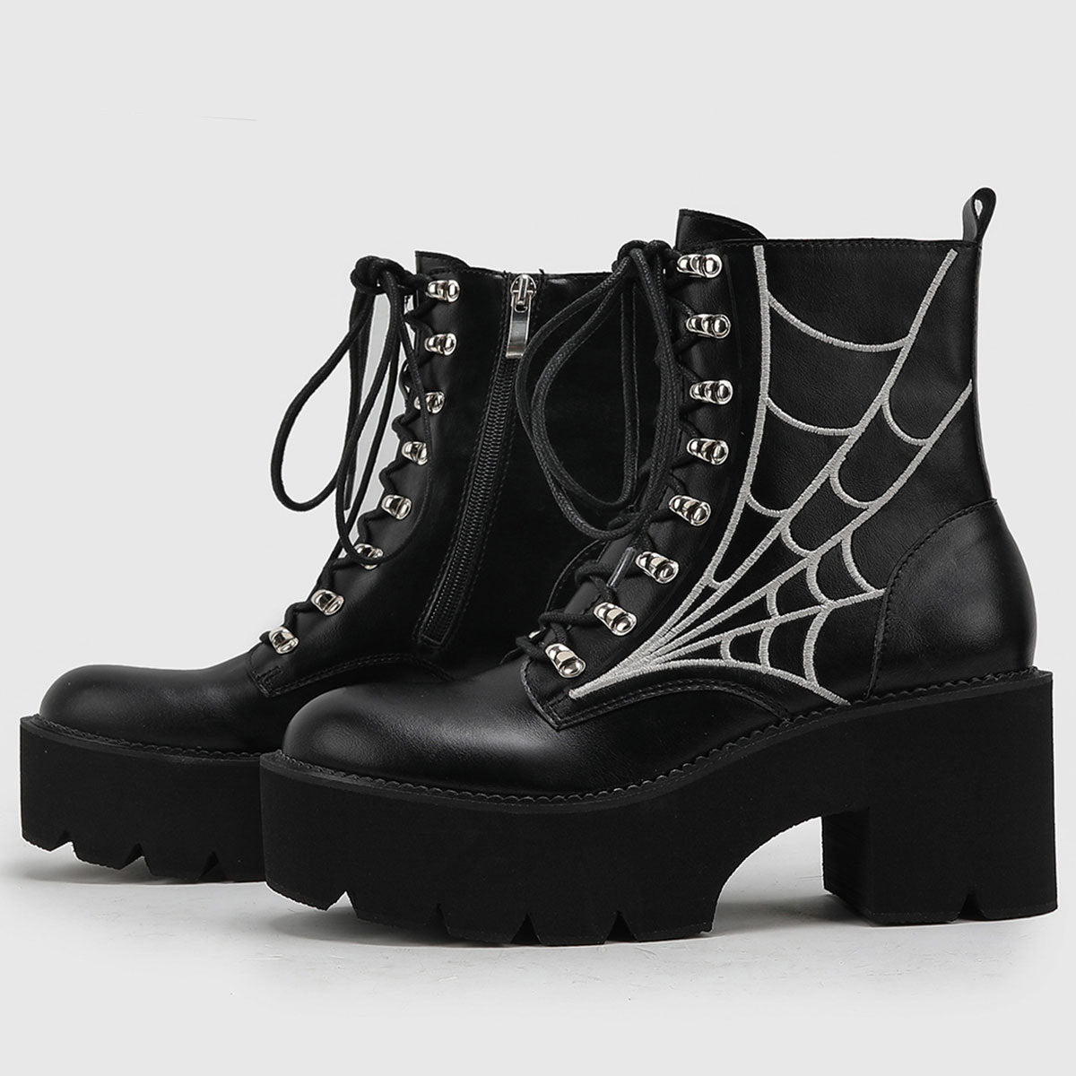 A pair of black women's platform combat boots with silver spiderweb embroidery, lace-up front, and side zipper, displayed on a white background.
