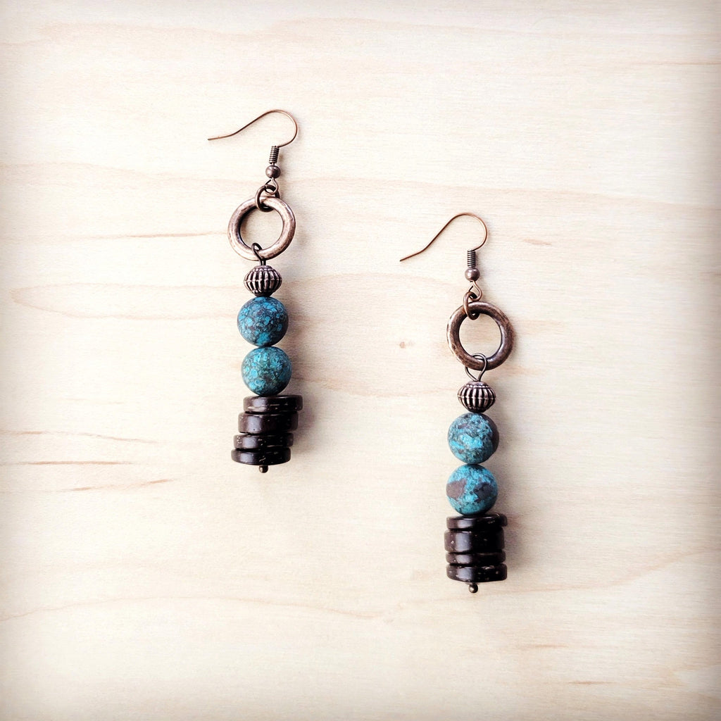 Natural American turquoise and dark wood bead drop earrings with copper-tone hook closures on a light wood background.